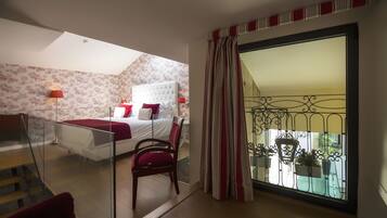A bedroom with a bed, a chair, a window with curtains, and a balcony with plants.