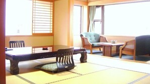Una habitación japonesa tradicional con suelo de tatami, una mesita baja y dos sillas.