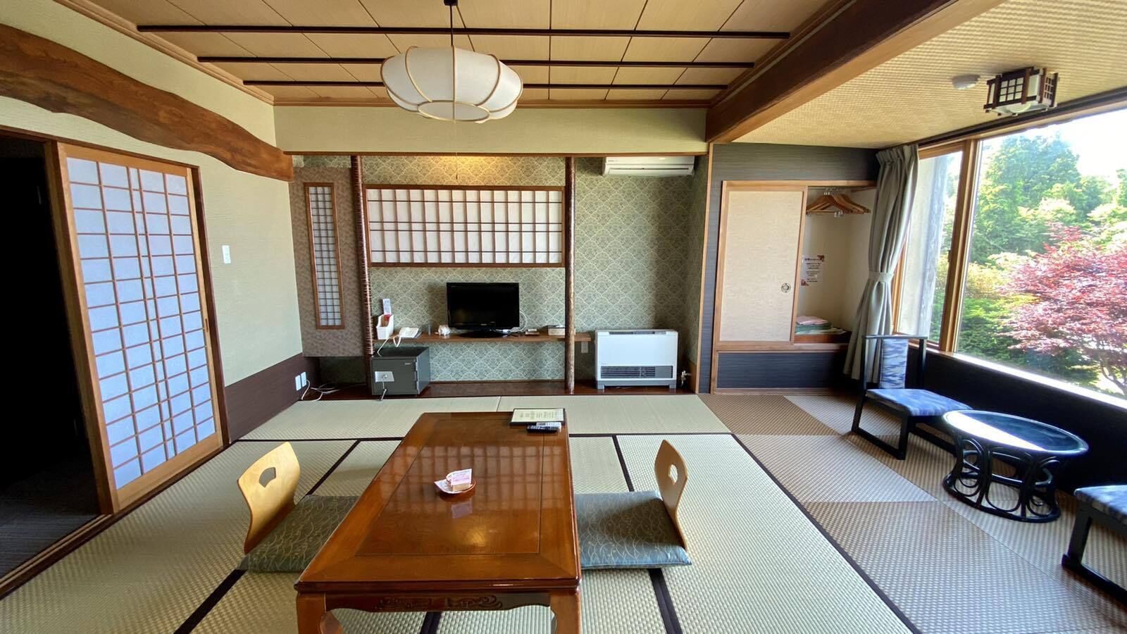 A traditional Japanese room with tatami flooring, a low table with cushions, a television, and a sliding door.