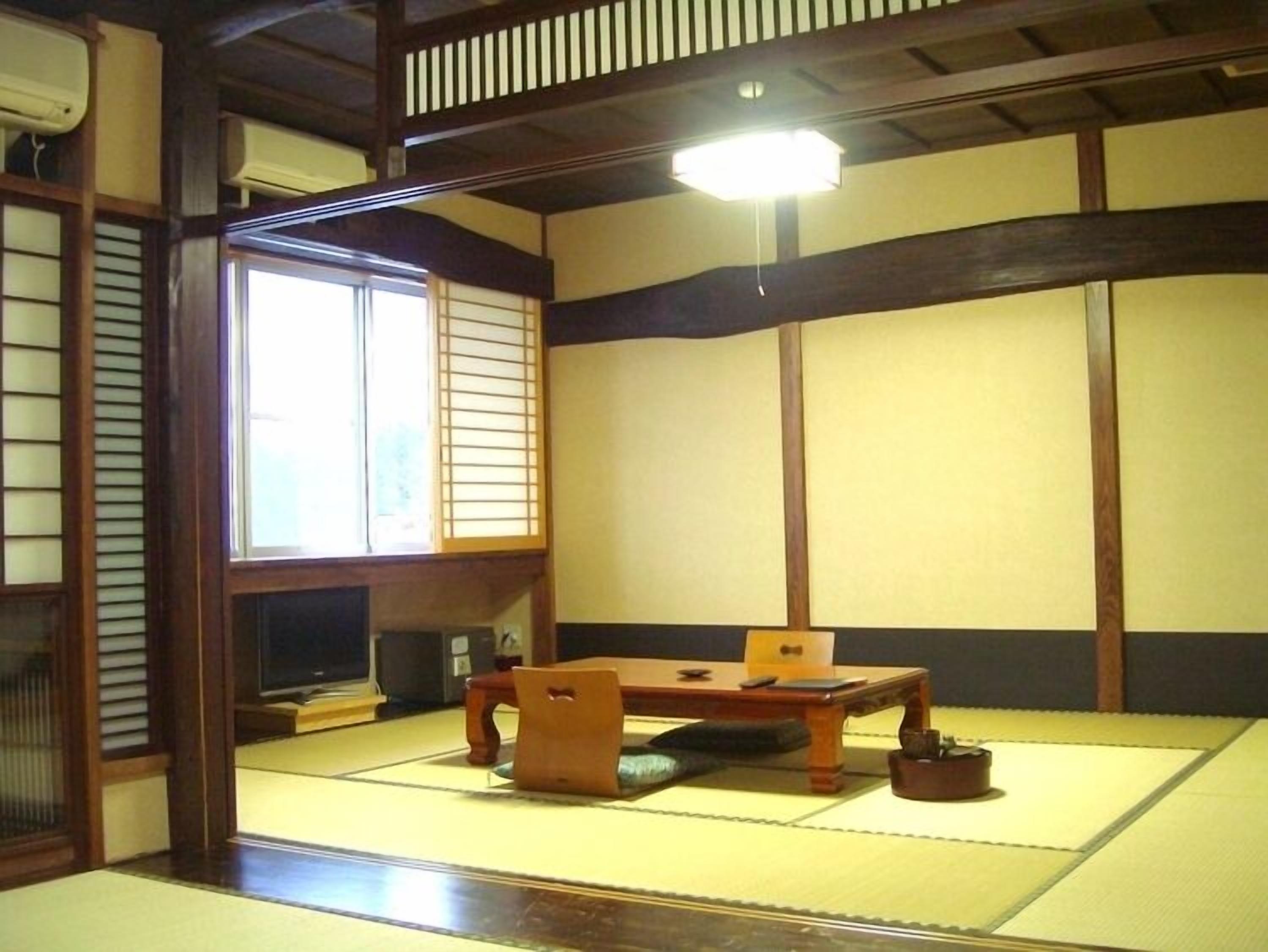 A traditional Japanese room with tatami flooring, a low wooden table, and sliding doors.