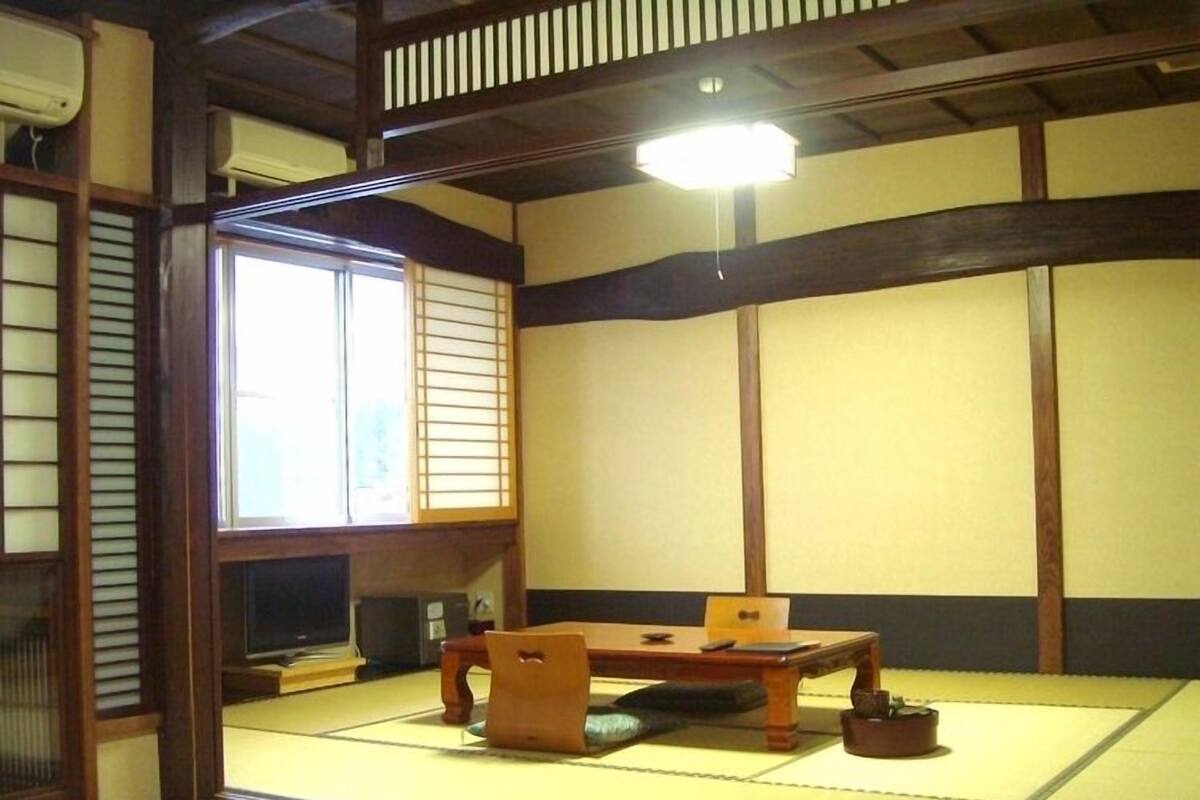 A traditional Japanese room with tatami flooring, a low wooden table, and sliding doors.