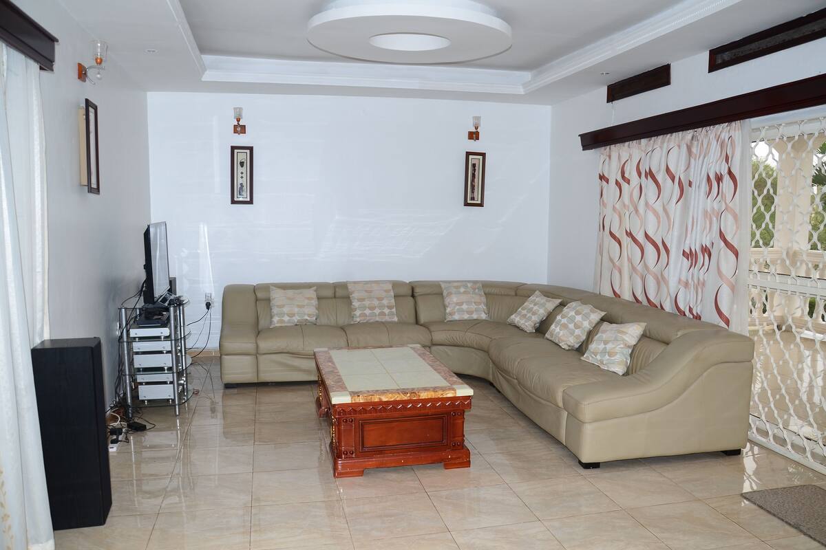 A living room with a sectional sofa, a wooden coffee table, and a TV stand.