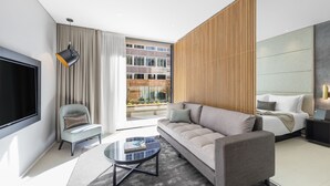 A modern hotel room with a sofa, armchair, and a flat-screen TV. - SKYE Suites Sydney (Sydney)