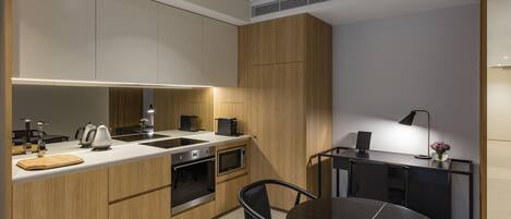 A modern kitchen with a central island, built-in oven, microwave, and a dining area with a round table and chairs.
