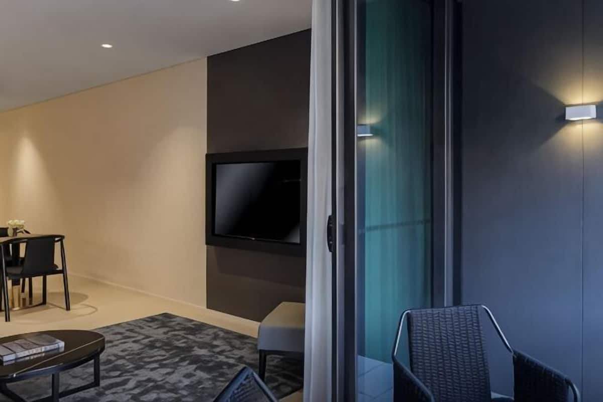 Ein modernes Wohnzimmer mit einem an der Wand montierten Flachbildfernseher, einer Couch, einem Couchtisch und einem kleinen Esstisch mit Stühlen.
