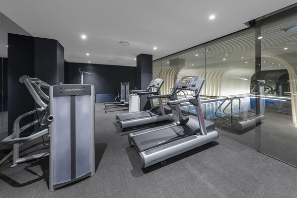 A modern gym with treadmills, elliptical machines, and a weight bench. - SKYE Suites Sydney (Sydney)