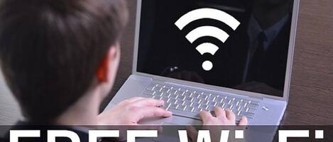 A person using a laptop with a Wi-Fi symbol on the screen, indicating free Wi-Fi availability.