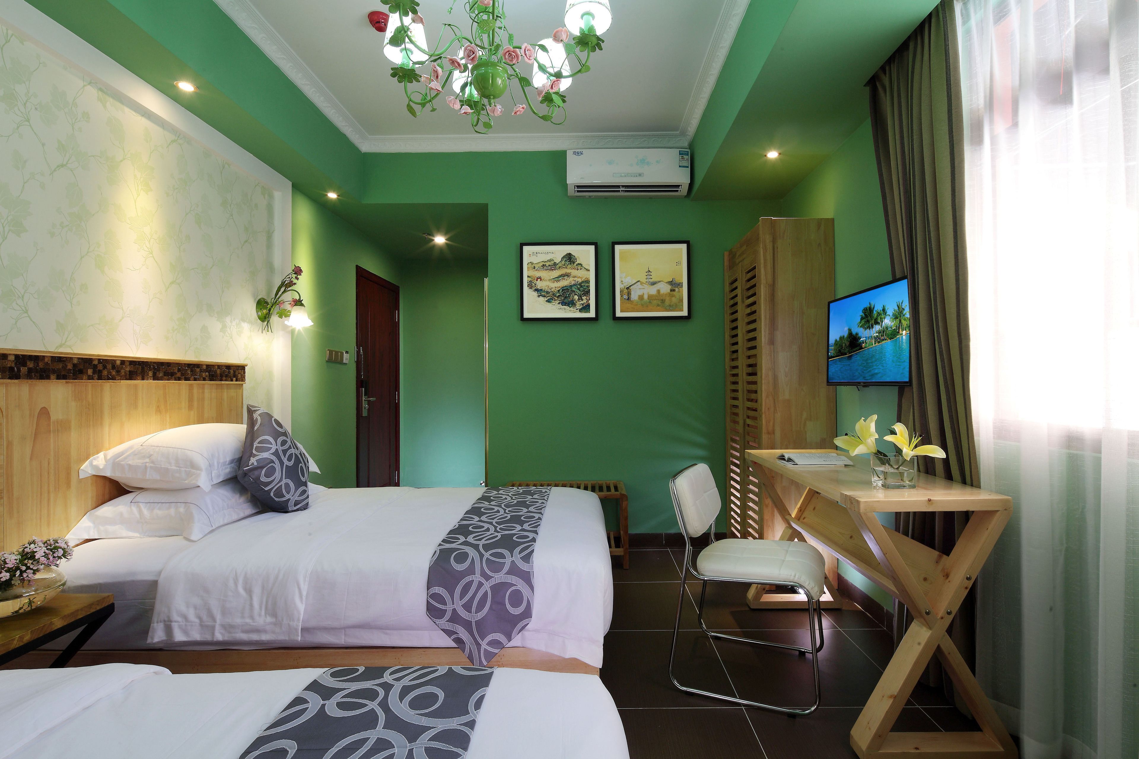 Une chambre d’hôtel avec deux lits, un bureau, une chaise et un téléviseur.