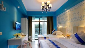 Quarto de hotel com duas camas, uma escrivaninha, uma cadeira, uma televisão e uma varanda com vista.