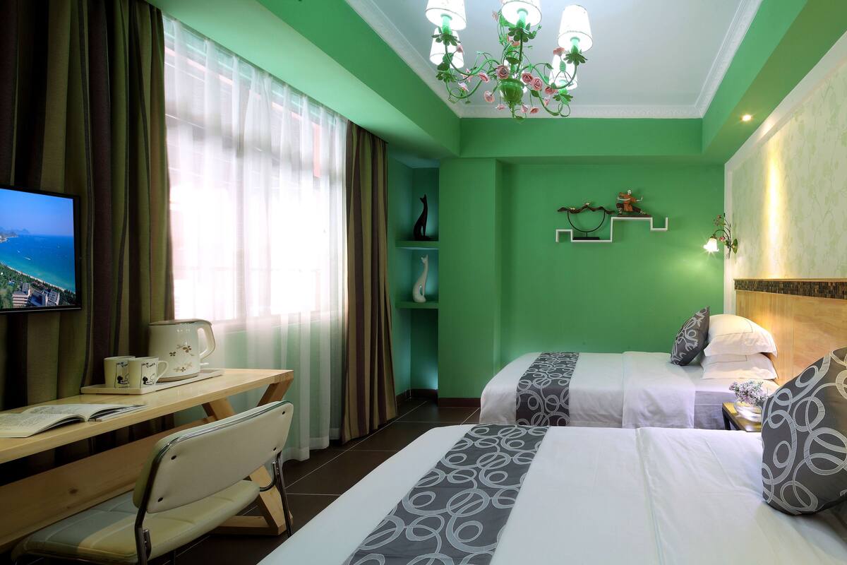 A hotel room with two beds, a desk with a chair, a television, and a window with curtains.