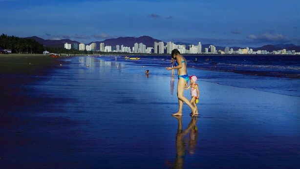 Uma praia com o horizonte da cidade ao fundo.