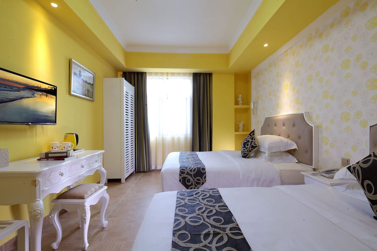 A hotel room with two beds, a desk, and a chair.