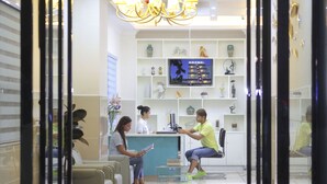 Uma área de recepção com design moderno, incluindo um balcão, sala de estar e um candelabro.