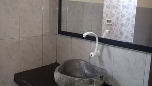 Une salle de bain avec un lavabo en pierre, un plan de toilette noir et un miroir à cadre noir.