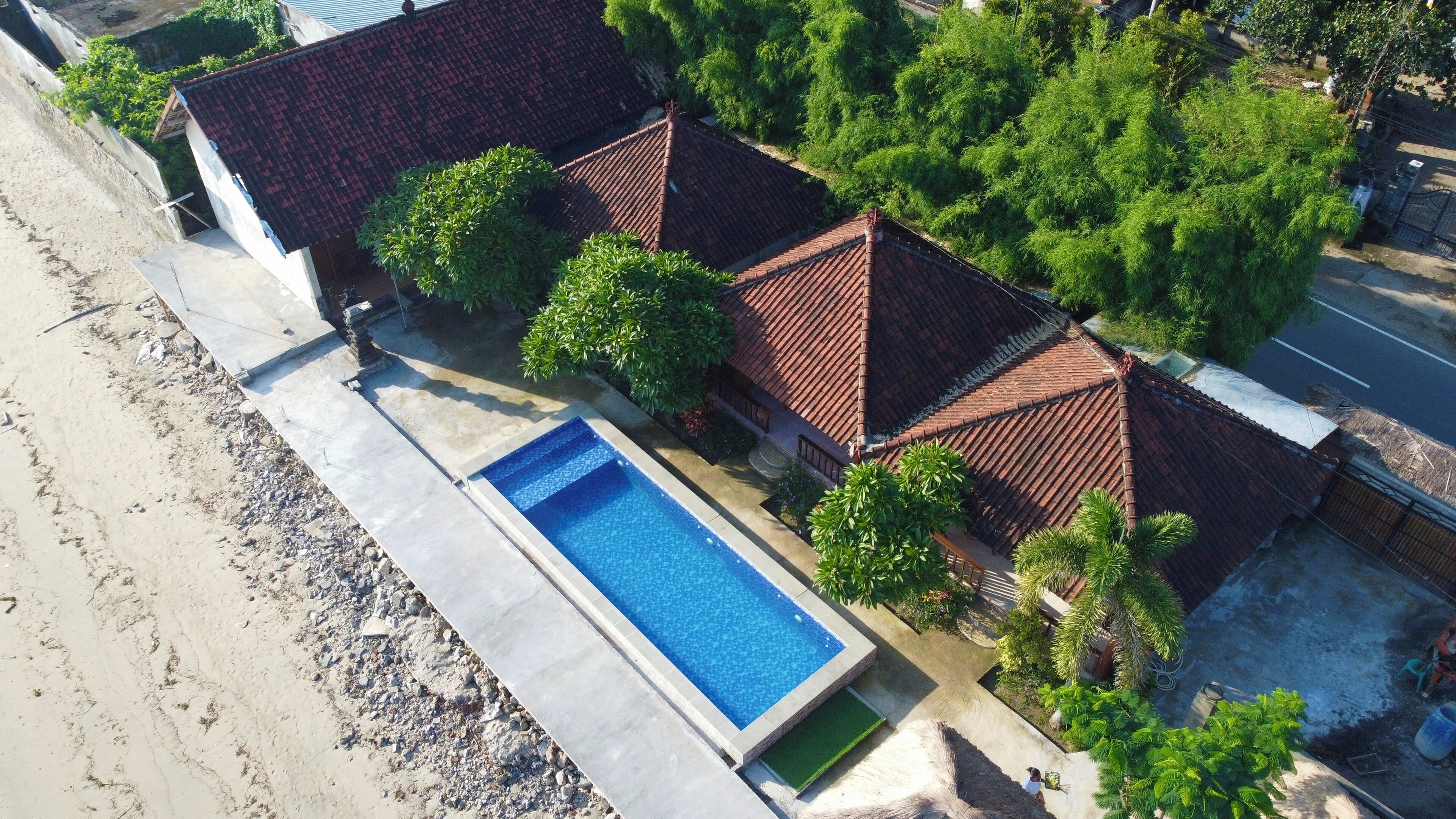 Propiedad residencial con piscina, techos de tejas y abundante vegetación.