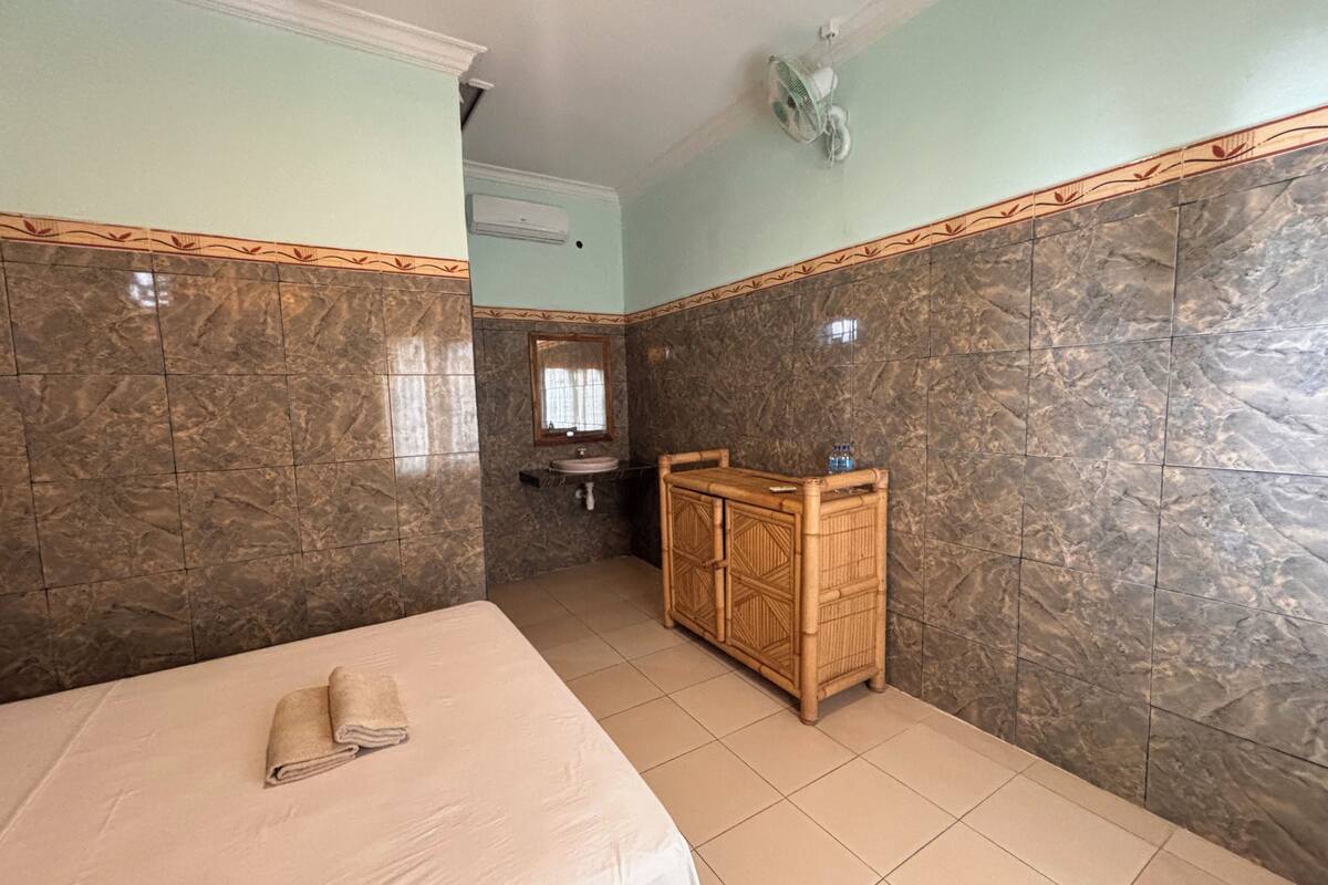 Una habitación de hotel con cama, un aparador de madera, un lavabo y un espejo.