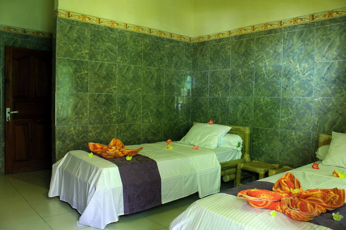 Una habitación de hotel con dos camas, una puerta de madera y paredes de mármol verde.