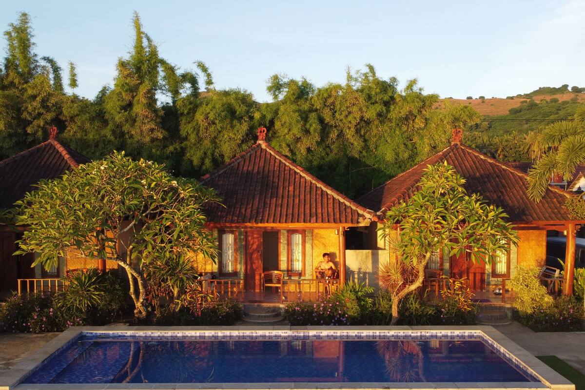 Una villa tradicional con piscina, rodeada de exuberante vegetación y colinas.