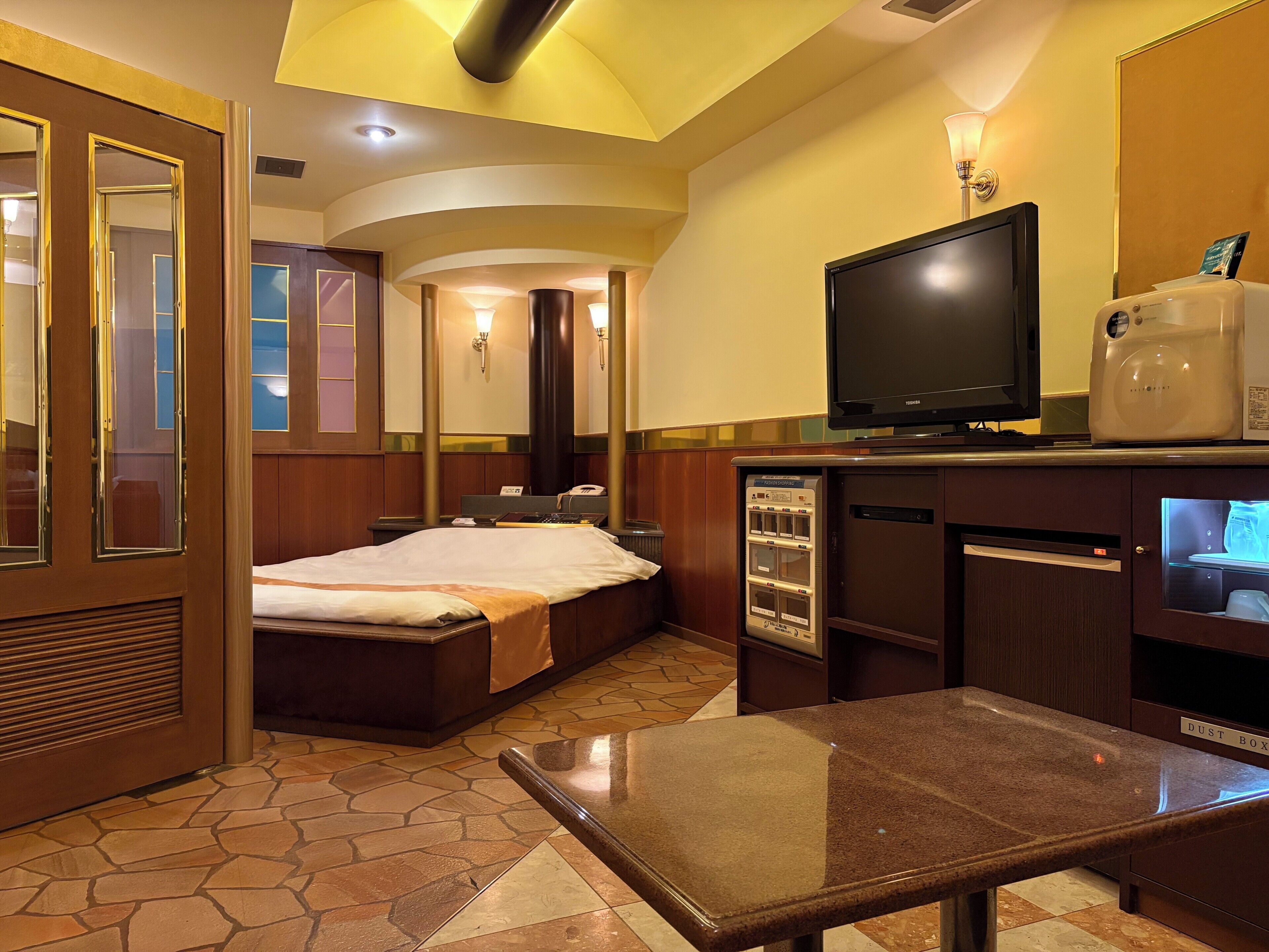 A hotel room with a bed, a television, a coffee maker, a desk, and a mirror.