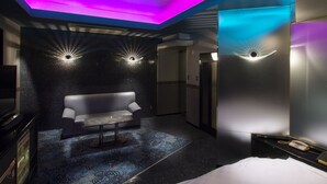 Una habitación de hotel moderna con sofá, una mesita y una cama.