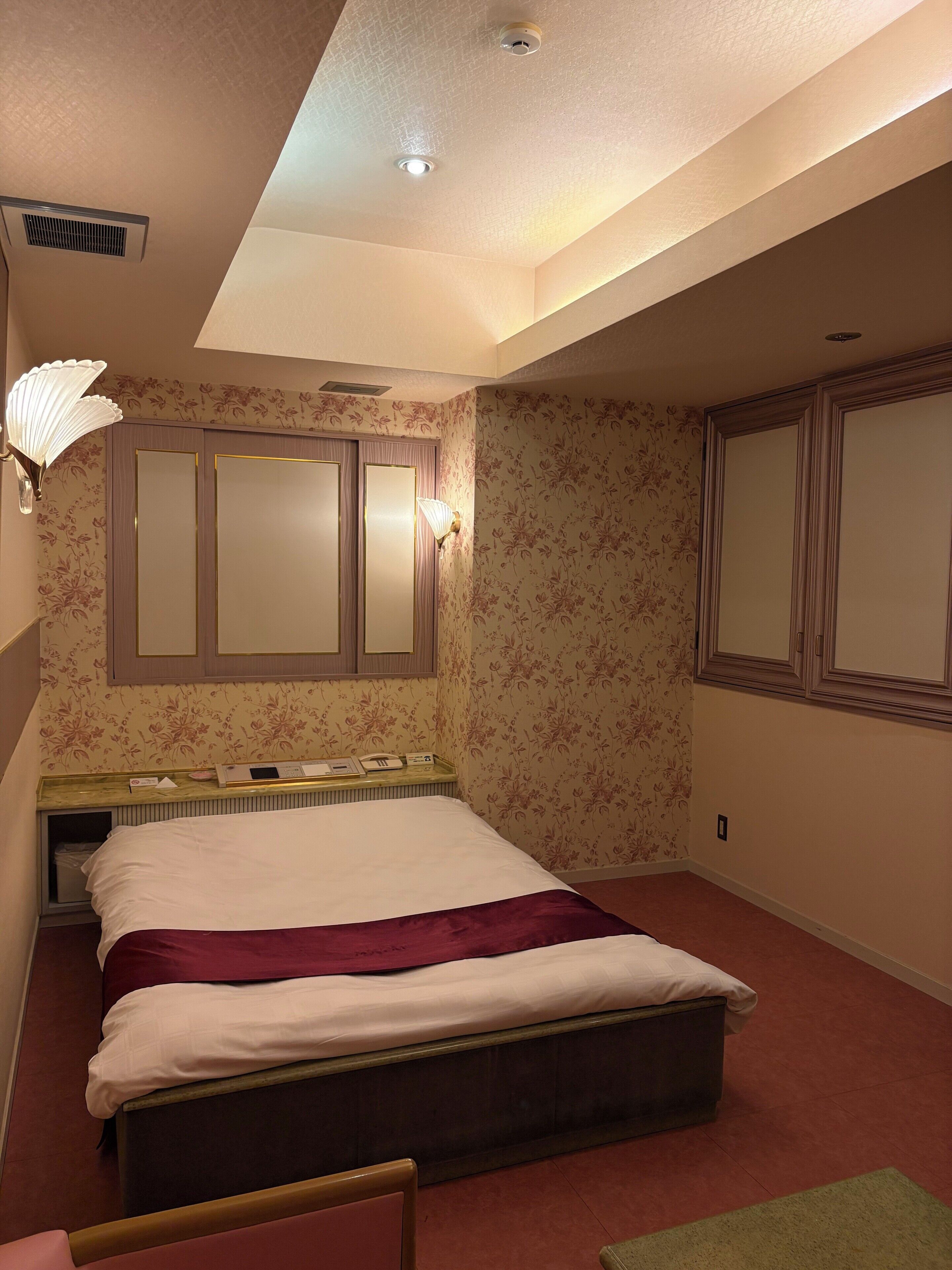 Un dormitorio con cama, un radiador, una lámpara de pared y un espejo.