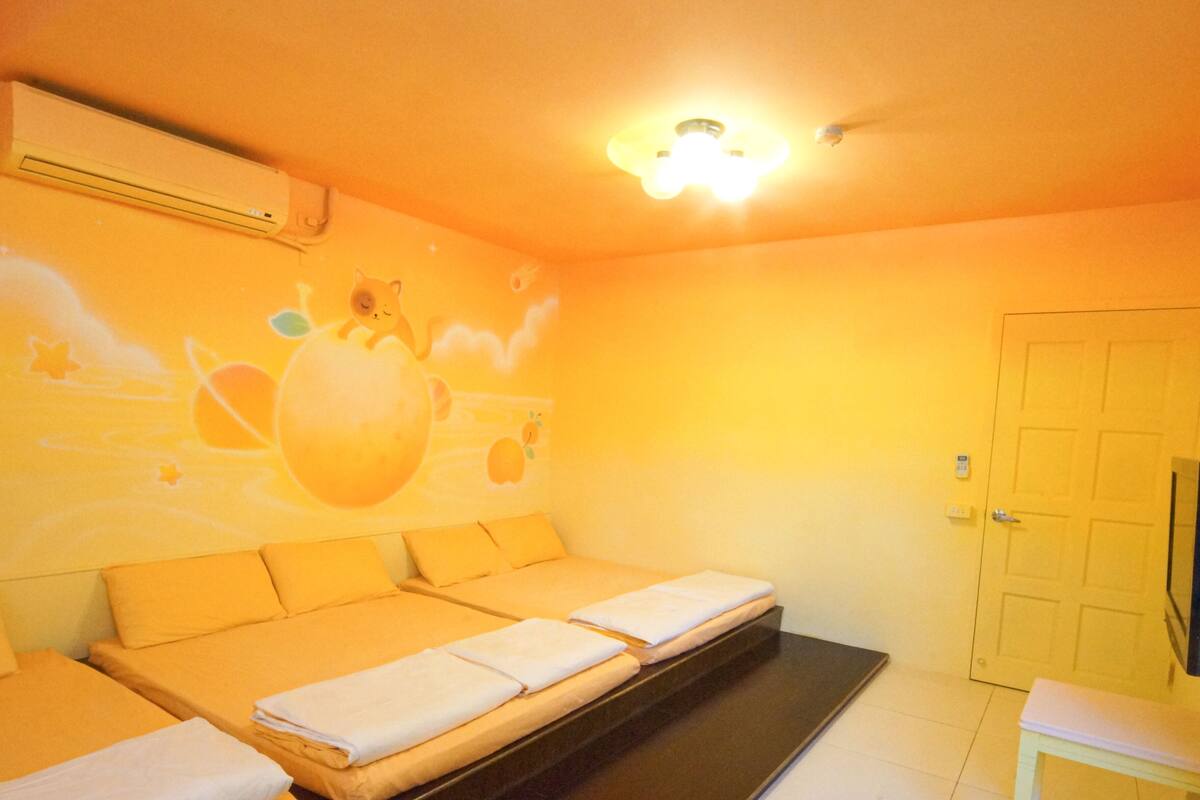 A room with a sofa bed, a small table, and a wall with a mural.