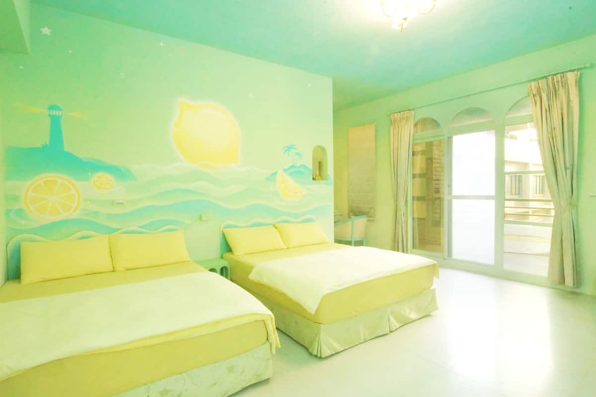 A room with two beds, a mural with a lighthouse, and a balcony with curtains.