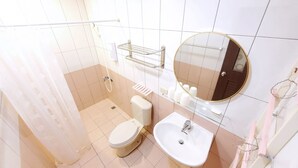 A bathroom with a toilet, sink, mirror, and shower area. - DingDing Home (Hengchun)