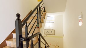 A staircase with black railings and marble steps, a wall-mounted light fixture, and a framed sign with Chinese characters. - DingDing Home (Hengchun)