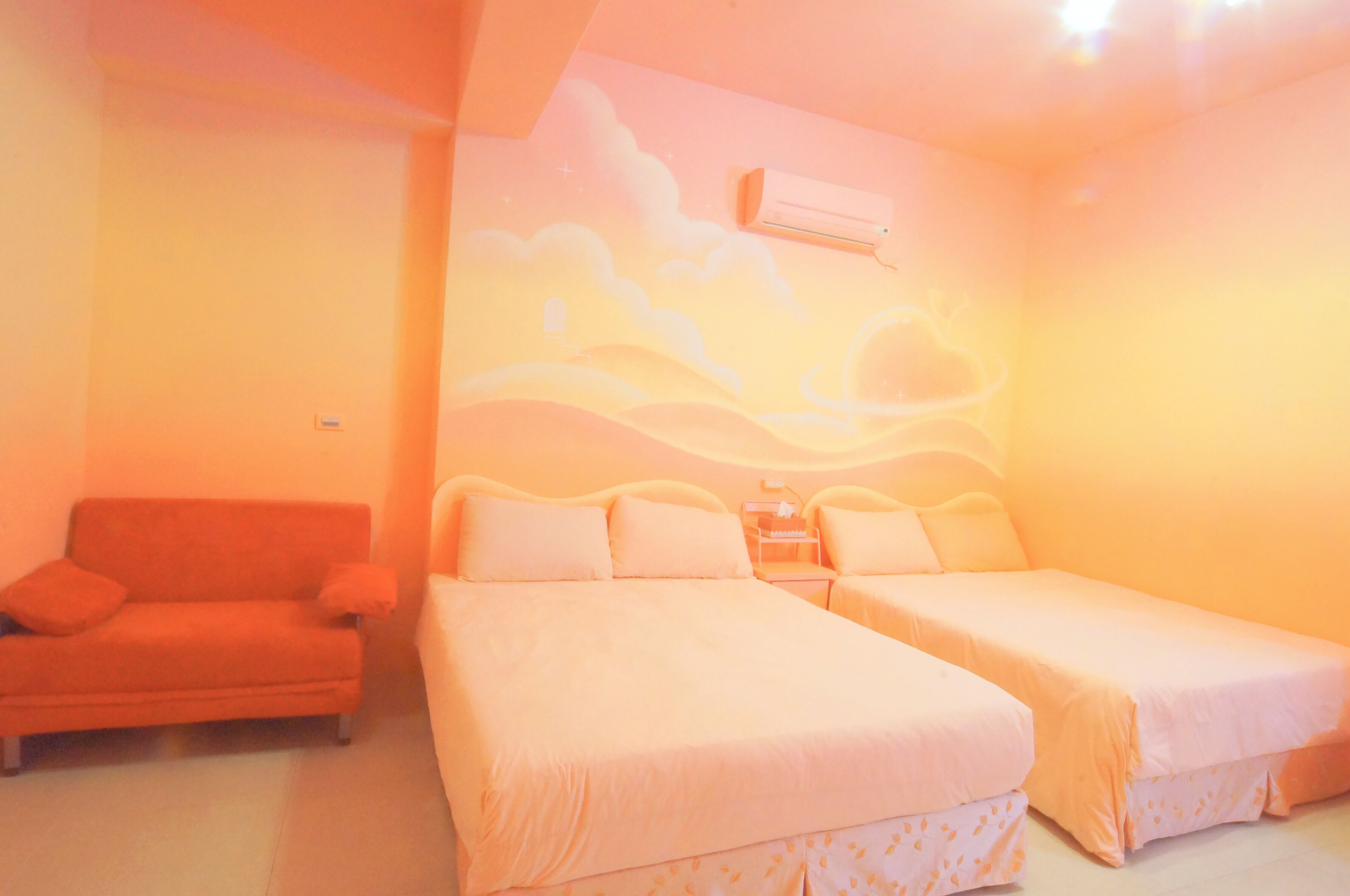 Una habitación con dos camas, un sofá y un equipo de aire acondicionado en la pared.
