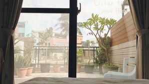 A bedroom with a large window, a bed, and potted plants. - Suiian inn  (Hengchun)