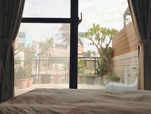 Ein Schlafzimmer mit großem Fenster, einem Bett und Topfpflanzen.
