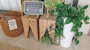 A wooden table with a chalkboard sign, a wicker basket, and potted plants. - Suiian inn  (Hengchun)