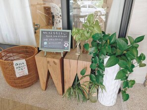Ein Holztisch mit einer Kreidetafel, einem Korbwägelchen und Topfpflanzen.