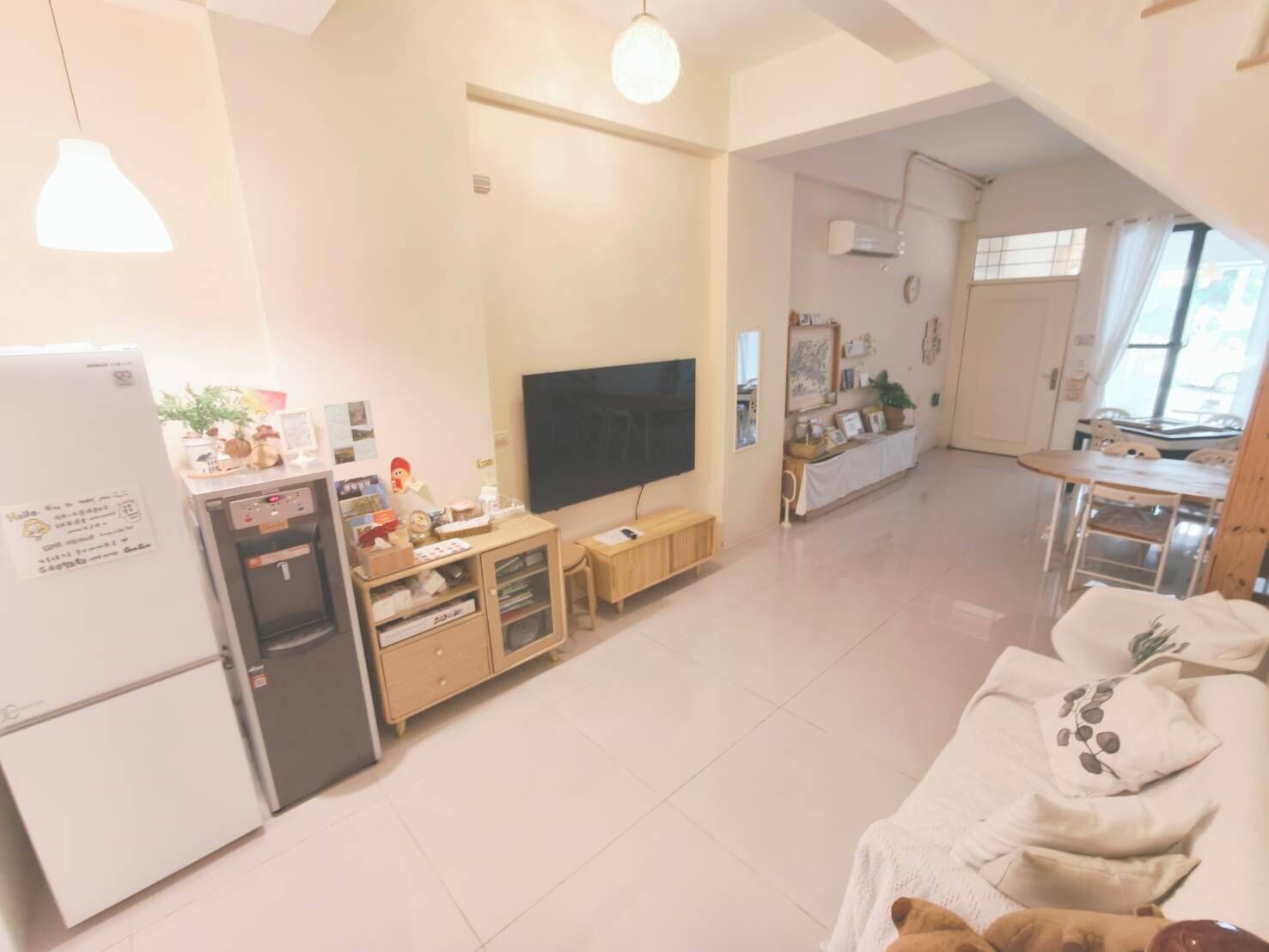 A spacious living area with a TV, wooden cabinets, a refrigerator, and a dining table.
