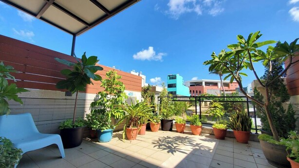A rooftop terrace with potted plants, a blue chair, and a view of the cityscape. - Suiian inn  (Hengchun)