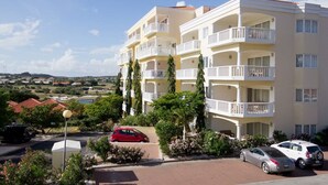 A multi-story hotel with balconies, a parking area, and a view of the surrounding landscape. - The Hill 25 – Elegant Apartment Near Blue Bay Beach & Golf Course, Curaçao (Sint Michiel)