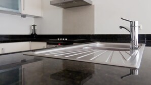 A modern kitchen with a stainless steel sink, black countertop, and white cabinetry. - The Hill 25 – Elegant Apartment Near Blue Bay Beach & Golf Course, Curaçao (Sint Michiel)