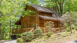 A wooden cabin with a porch, surrounded by trees and a stone pathway. - Secluded,-Private,Free WIFI,Pool Table,Hot Tub, Jacuzzi, 400 Game Arcade  (Pigeon Forge)