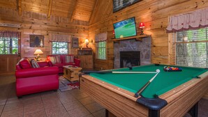 A cozy room with a pool table, red sofa, and a fireplace. - Secluded,-Private,Free WIFI,Pool Table,Hot Tub, Jacuzzi, 400 Game Arcade  (Pigeon Forge)
