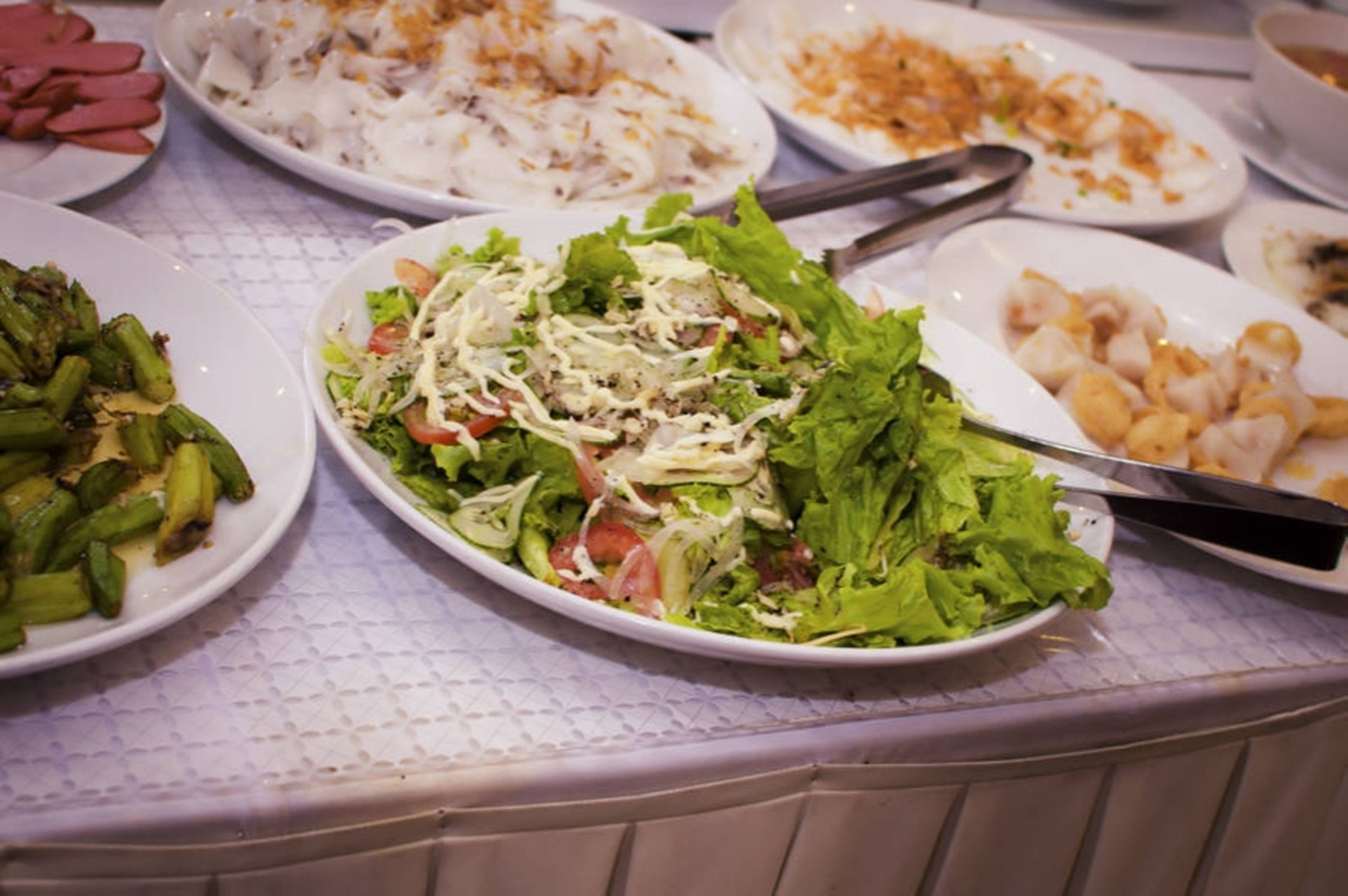 Una mesa de buffet con diversos platos, entre ellos ensaladas, verduras y mariscos.