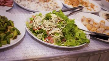 Una mesa de buffet con diversos platos, entre ellos ensaladas, verduras y mariscos.