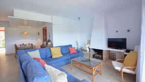 A living room with a blue sofa, a coffee table, a TV, and a fireplace. - Holiday rental apartment with swimming pool in Begur, Aiguablava (Begur)