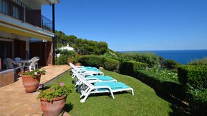 A terrace with sun loungers, potted plants, and a view of the sea. - Holiday rental apartment with swimming pool in Begur, Aiguablava (Begur)