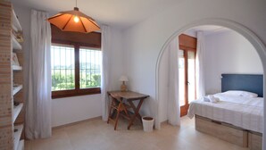 A bedroom with a bed, a desk, and a view through a window. - Holiday rental apartment with swimming pool in Begur, Aiguablava (Begur)