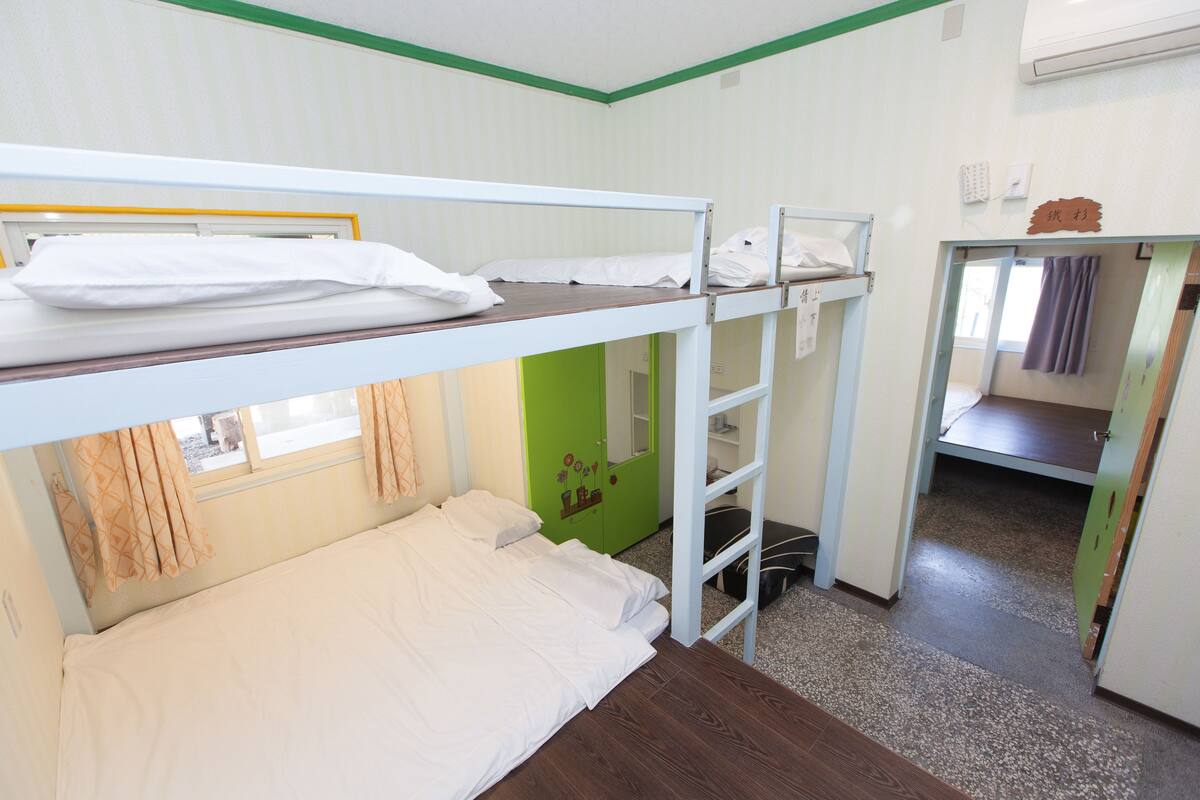 A bunk bed room with a green door and a small window.