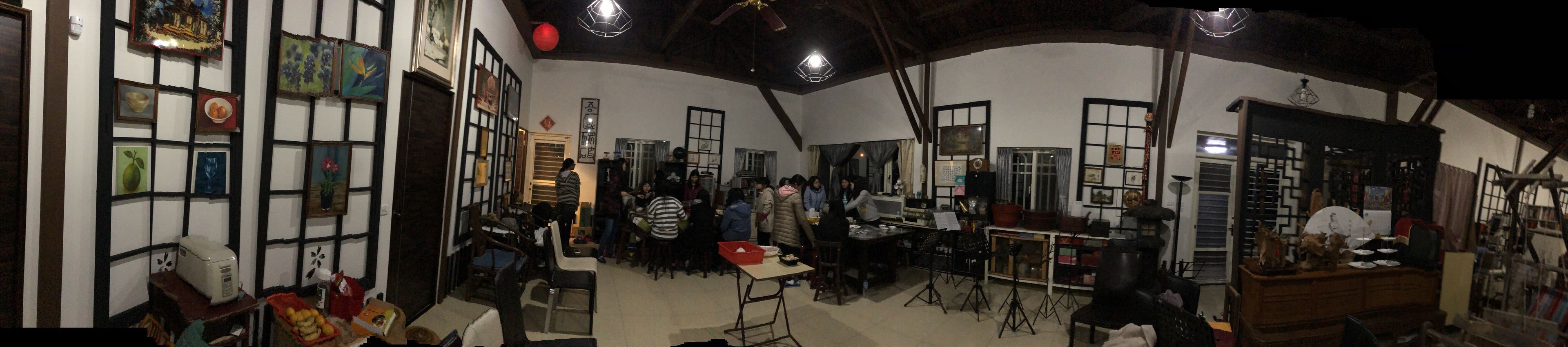 A traditional interior with wooden beams, tiled walls, and a communal dining area with tables and chairs.