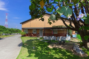 A two-story building with a white picket fence, a paved driveway, and a grassy lawn. - 512 Huts Homestay (Dongshan)