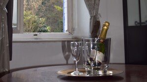 A window with curtains, a bottle of champagne, and two glasses on a table. - Maison des Ingénieurs (Molieres-sur-Ceze)