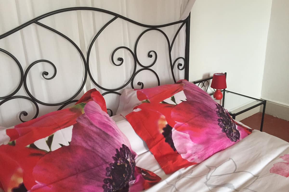 Un lit avec une tête de lit en métal et une literie à motifs floraux.